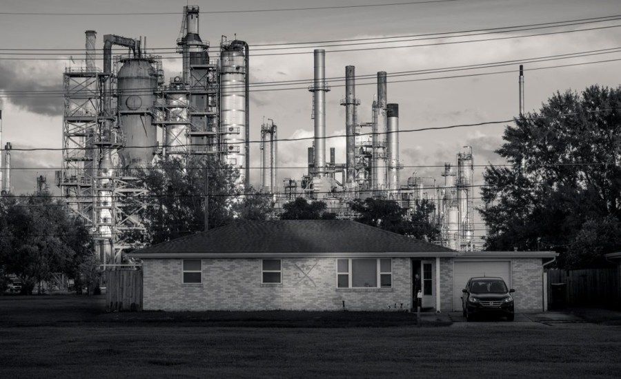 a photo of a ranch house with an oil refinery in the background