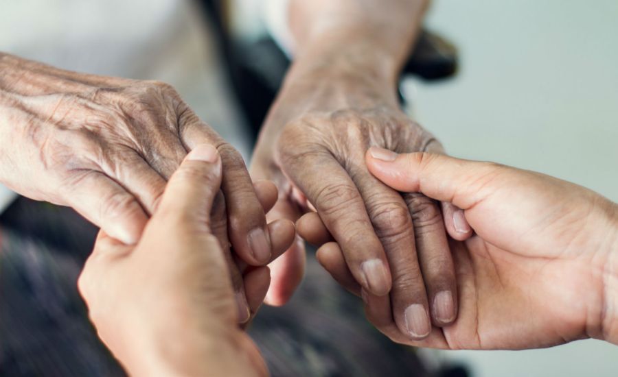 Photo of a young person's hands holding an elderly person's hands