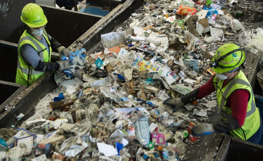 a photo of workers sorting recyclables at a recycling facility