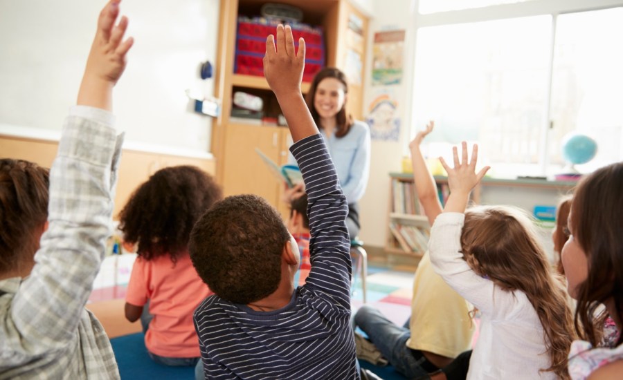 Children raise their hands in a classroom