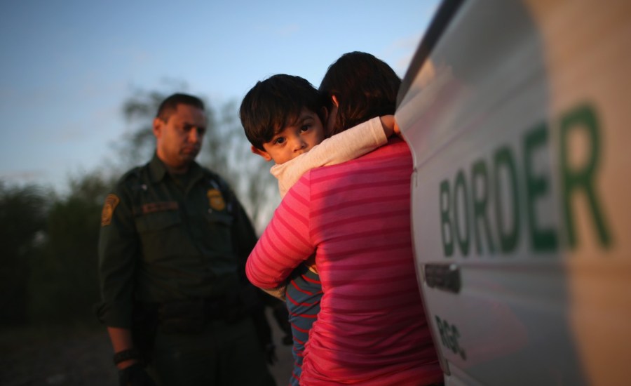 A young immigrant child clings to his mother after she turns herself in to US border patrol