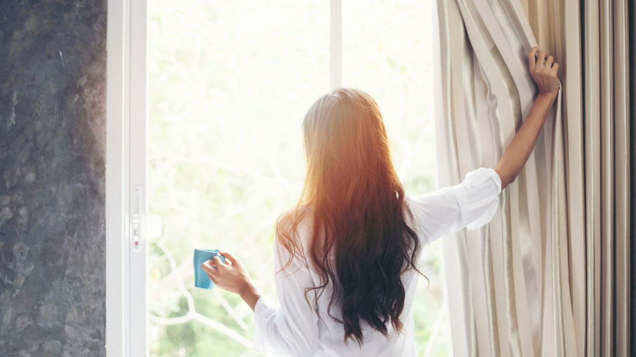 a woman holds a cup of coffee in the morning.