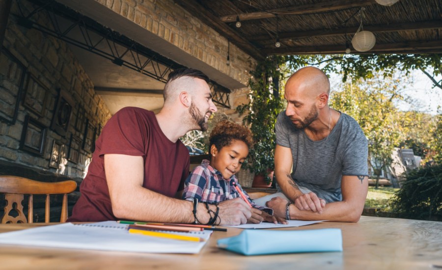 A gay couple sits with their child at a table.