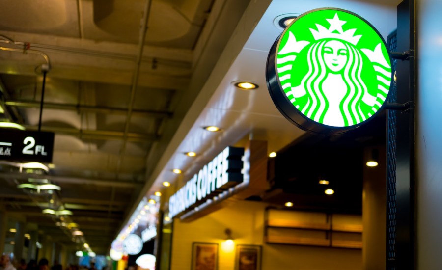 the starbucks name and logo above a airport coffee shop