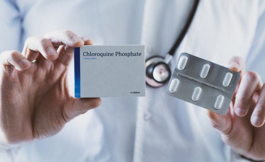 a doctor holds up a box of chloroquine phosphate with four tablets