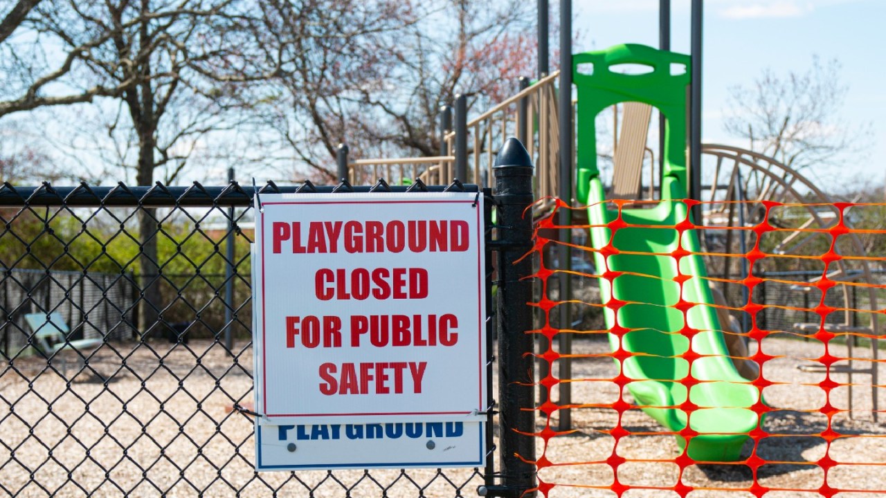 a playground closed off with orange tape and a sign