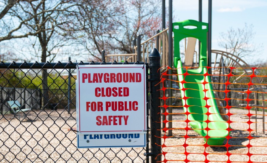 a playground closed off with orange tape and a sign