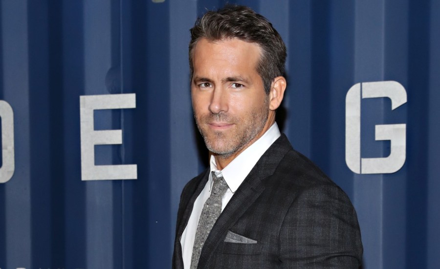 actor ryan reynolds in a suit on a red carpet