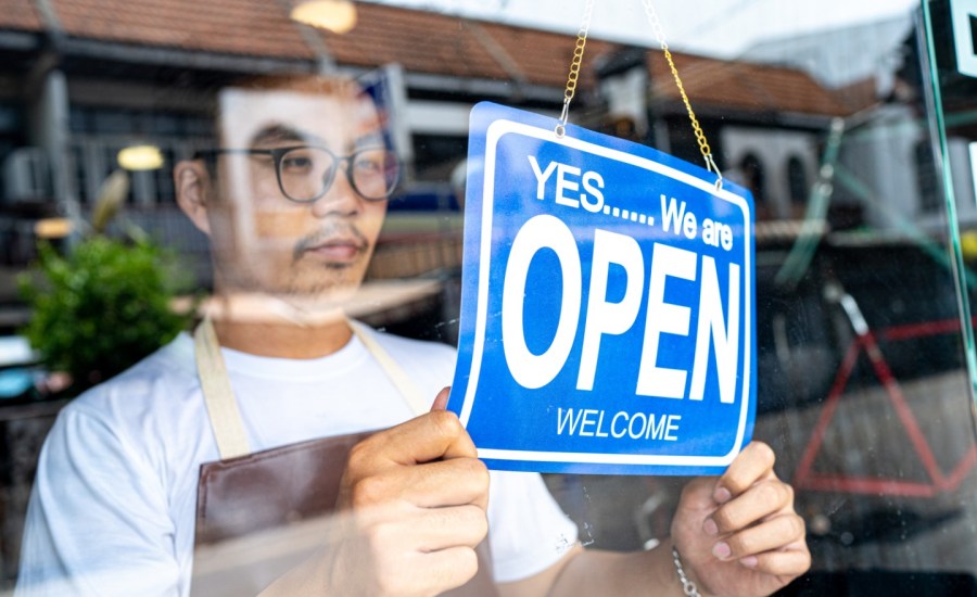 a store worker flips an open sign in the window