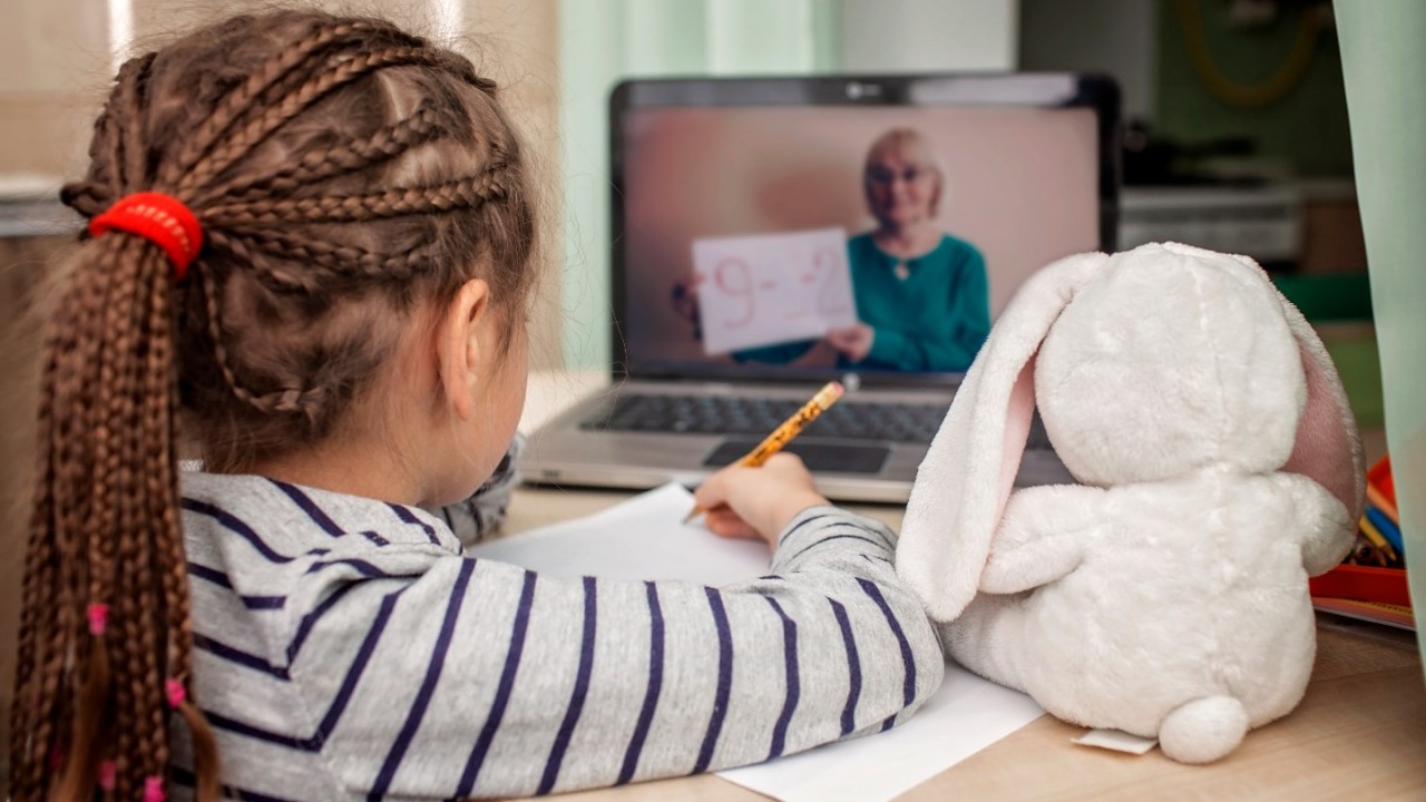 a girl watches her teacher on a laptop