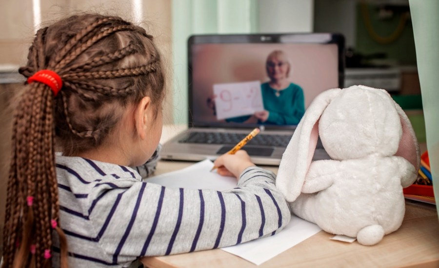 a girl watches her teacher on a laptop