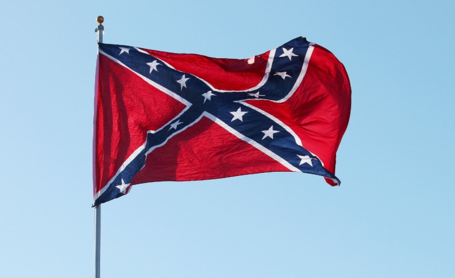 a confederate flag flies against a blue sky