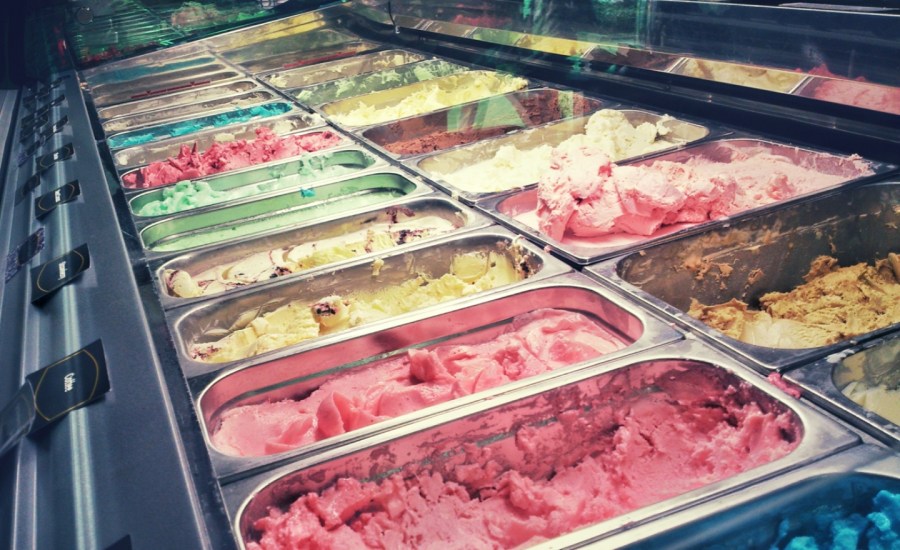 bins of ice cream flavors behind a glass in a store