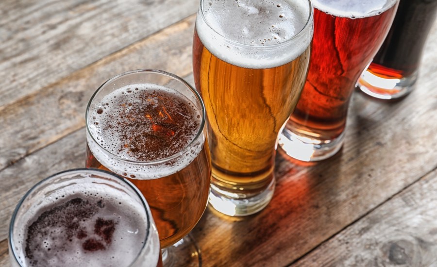 Glasses with different types of cold tasty beer on wooden table