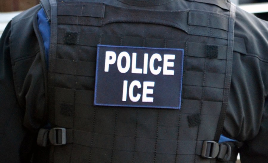 the back of an officer's vest reads "POLICE ICE"