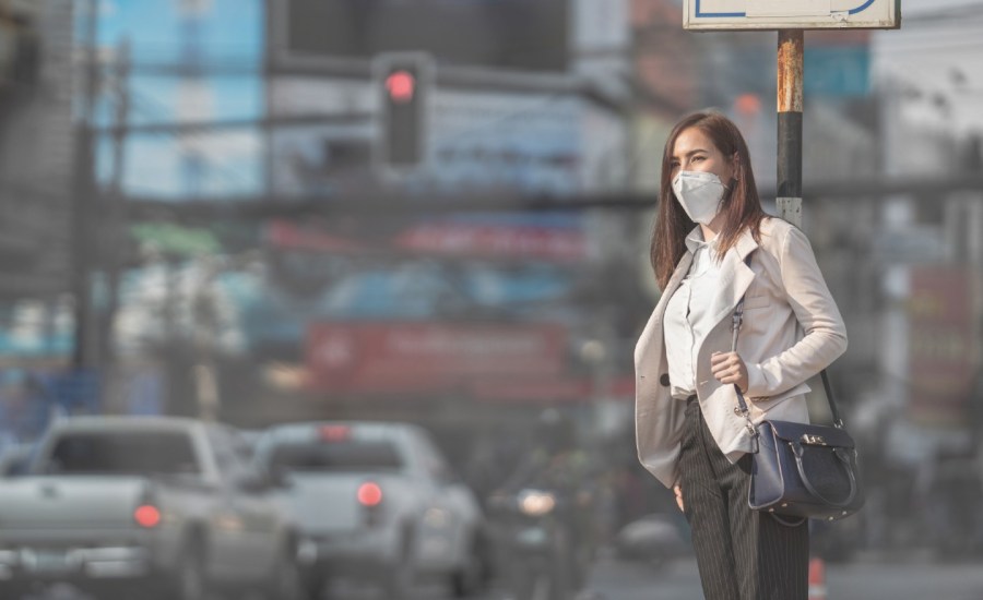 woman in a mask on a polluted street with cars