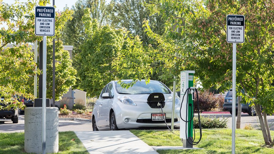 An electric or hybrid vehicle is shown charging in an area of the parking lot designed for electric and low emission vehicles