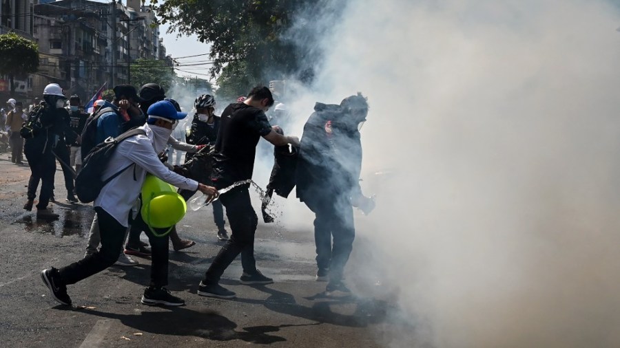 Protesters attempt to contain tear gas fired by police trying to disperse them during a demonstration against the military coup in Yangon on February 28, 2021.