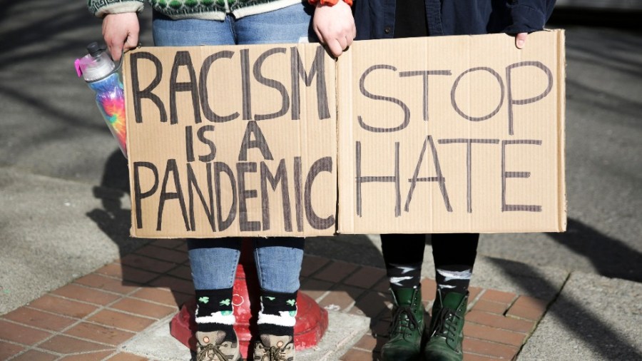 Signs saying "Racism is a pandemic" and "Stop hate"