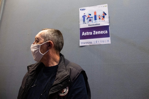 A man waits to get vaccinated near a sign indicating an Astra Zeneca vaccination area