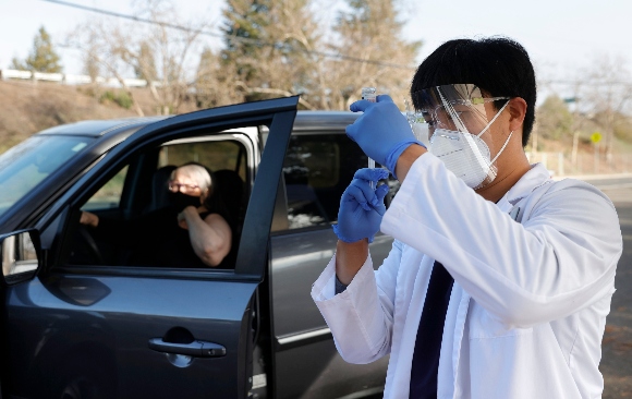 A pharmacist fills a syringe with Moderna COVID-19 vaccination during a drive-thru clinic