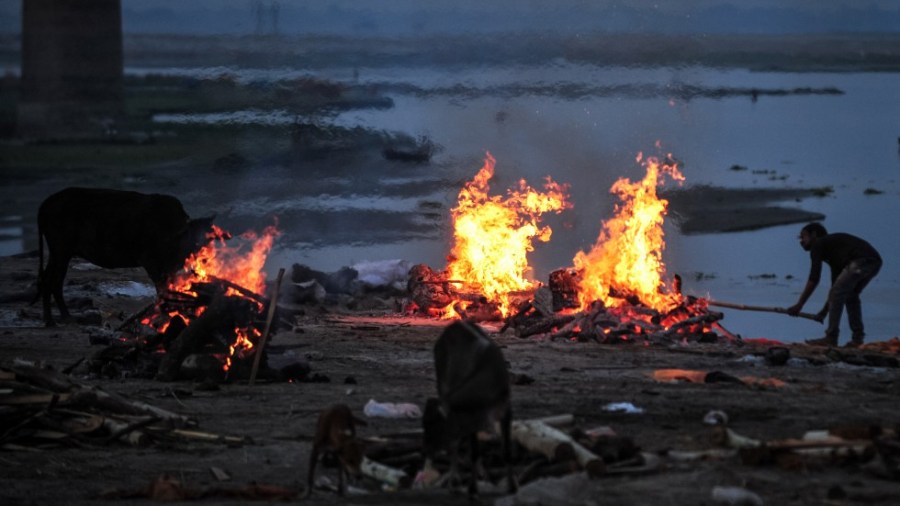 A worker cremates unclaimed bodies of people thought to have died from Covid-19 at a mass crematorium site on the banks of the Ganges river