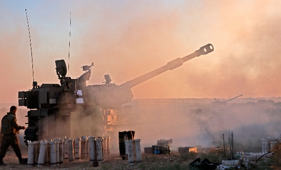 Israeli soldiers fire a 155mm self-propelled howitzer toward the Gaza Strip