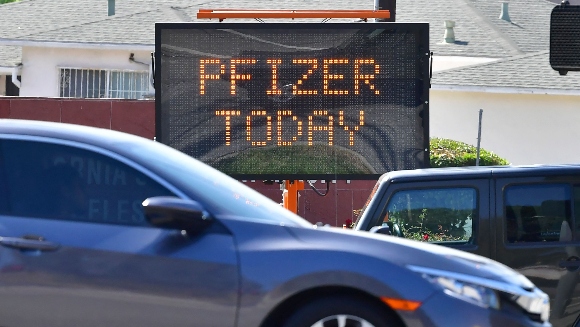 Motorists make their way past a sign announcing "Pfizer Today" at vaccination site