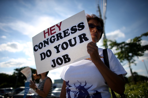 Omayra Hernadez holds a sign reading, "Hey Congress Do Your Job"