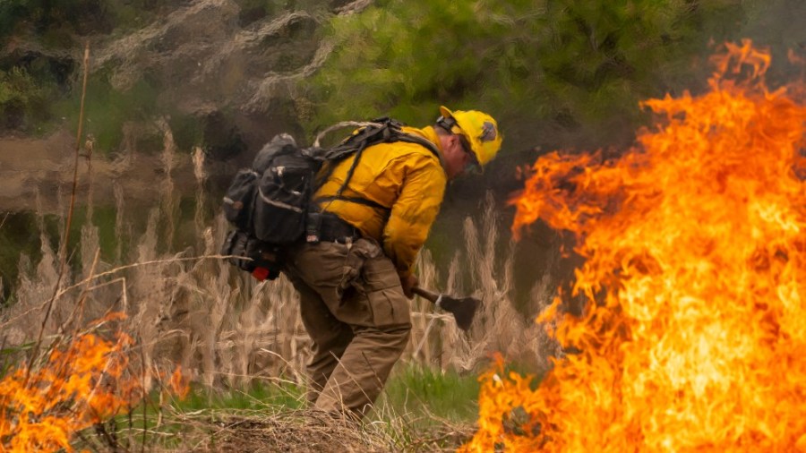 A volunteer firefighter practices with a live burn during a wildfire training course in Brewster, Wash.