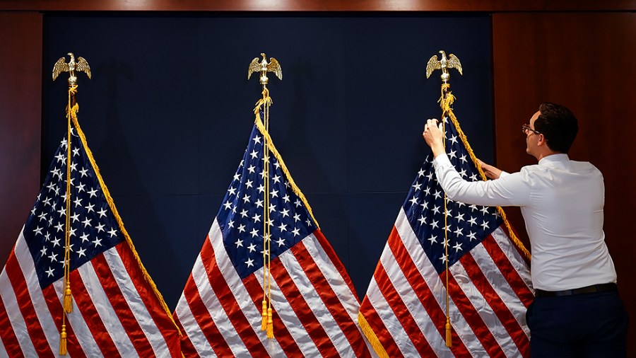 A staffer adjusts a flag prior to a media availability regarding a House Democratic Conference meeting on June 15