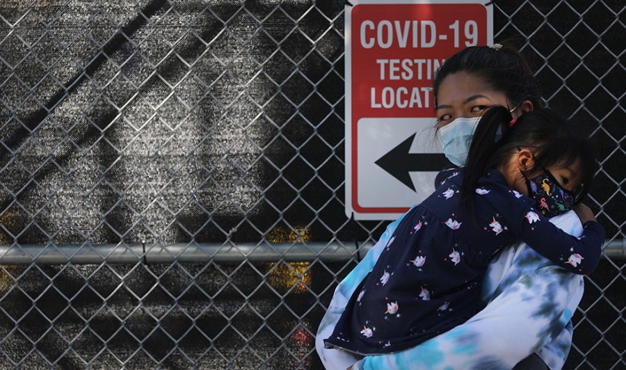 A mother and her child wait in line for a COVID-19 test