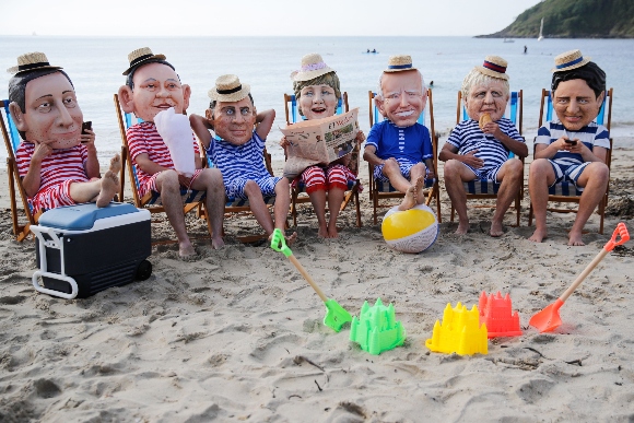 Oxfam activists wearing papier mache heads depicting G7 leaders perform during a protest