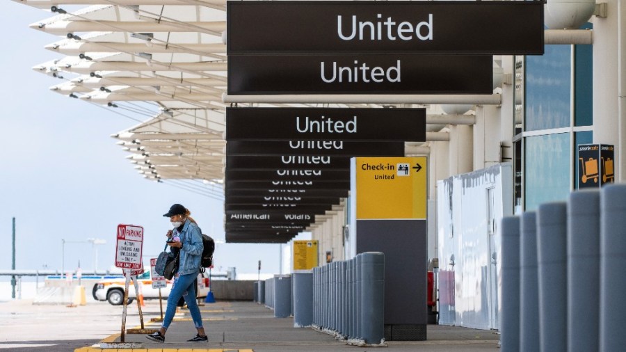 A woman walks to her car at an empty passenger drop off area at Denver International Airport