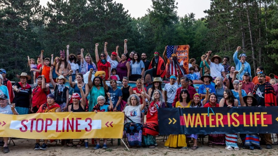 Environmental and climate activists alongside Native tribal community members pose for a picture following a Totem Pole consecration ceremony in Menahga, Minn.