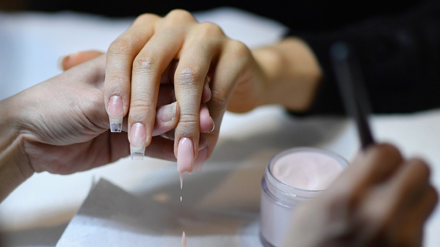 A woman gets her nails done in a light pink color