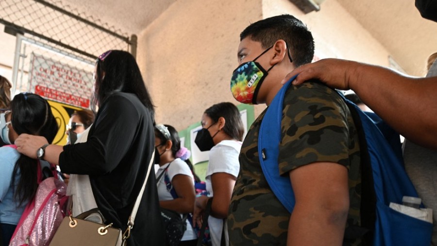 Students and parents wearing face coverings wait in line for the first day of the school year at Grant Elementary School in Los Angeles