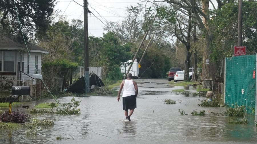 A man walks down a street flooded by Hurricane Ida in Kenner, La.