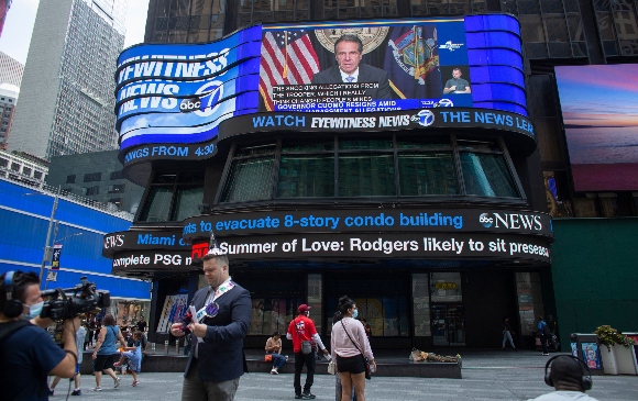 A screen shows news coverage of New York Governor Andrew Cuomo resigning over allegations of sexual harassment, in Times Square