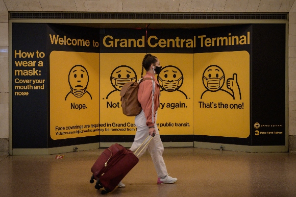 A poster advises travellers to wear face masks at Grand Central station in New York