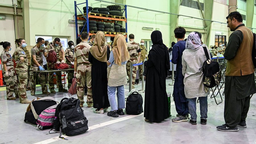 Refugees wait in line to have their baggage checked so they can leave Kabul.