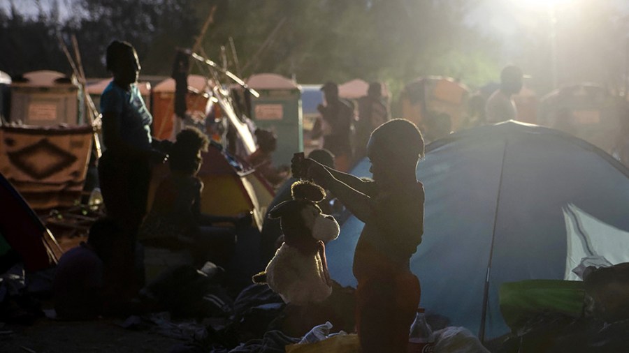 A boy plays with a toy puppy at a migrant camp on the U.S.-Mexico border