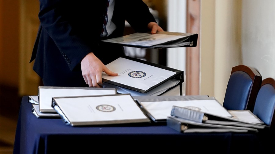 A staffer takes binders regarding the bipartisan infrastructure plan outside a meeting of Senate on Wednesday, July 28, 2021.