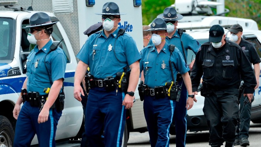 Massachusetts state police walk down a road near a protest outside the State House in Boston