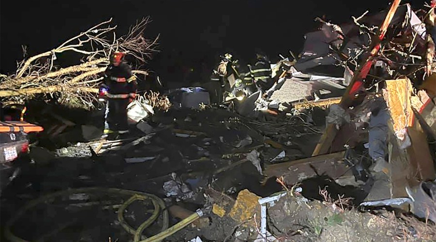 A firefighter walks through debris from homes after a tornado