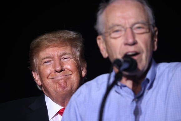 Former President Donald Trump smiles as Sen Chuck Grassley (R-IA) speaks during a rally