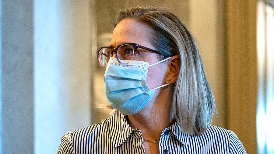 Sen. Kyrsten Sinema (D-Ariz.) speaks to Sen. Mitt Romney (R-Utah) as she leaves the Senate Chamber for votes regarding judicial nominations on Wednesday, October 27, 2021.