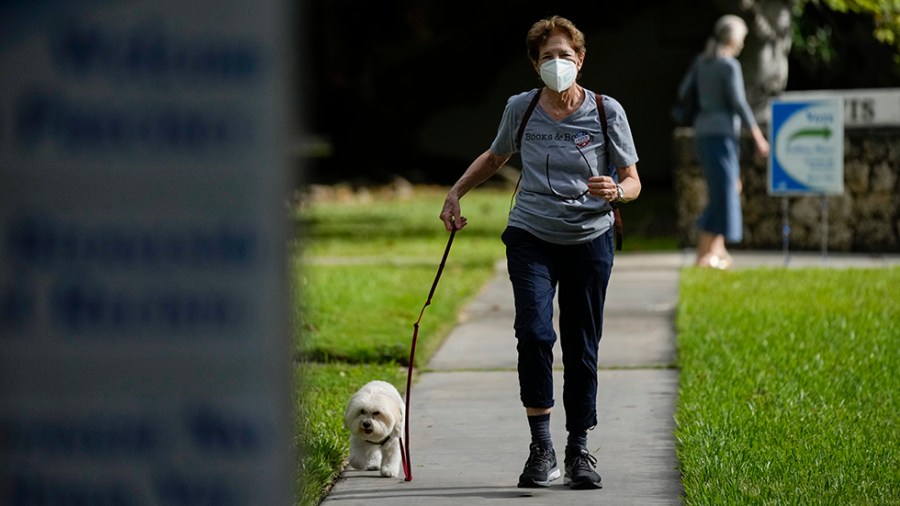 A woman walks with her dog away from a polling place after voting