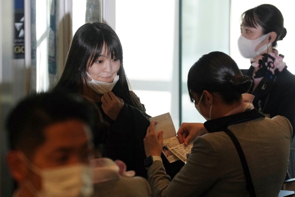 Japan's former Princess Mako, left, the elder daughter of Crown Prince Akishino, takes her mask off at a boarding gate to board an airplane to New York