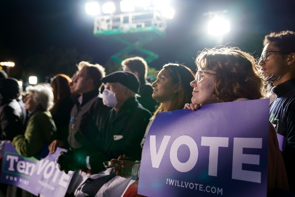 People listen as President Joe Biden speaks at a rall